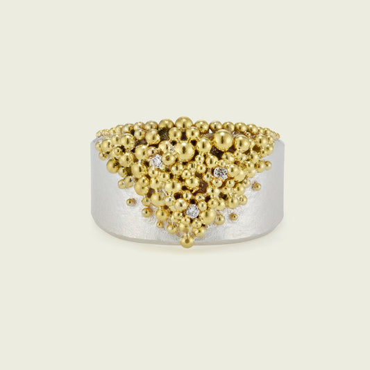 A quiet dialogue unfolds between silver and gold in this unique design - their contrast softened by the gentle flow of granulation. A generous band of silver is crowned with gold granules that cascade and taper into a single, fluid point. Interspersed are three twinkling diamonds, honoring my client’s children and grandchildren.