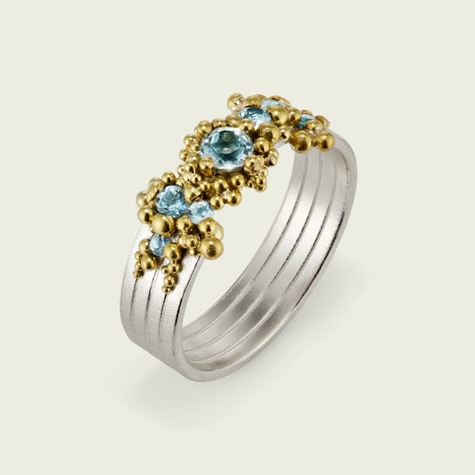This ring evokes the quiet motion of water - in a whorl of repurposed precious elements. My client's 14ct yellow gold formed the granulation that drifts across the surface of the silver ring and surrounds the jewels like seafoam. Her own central topaz is flanked by scatterings of aquamarines - selected for their clarity and pale brilliance.